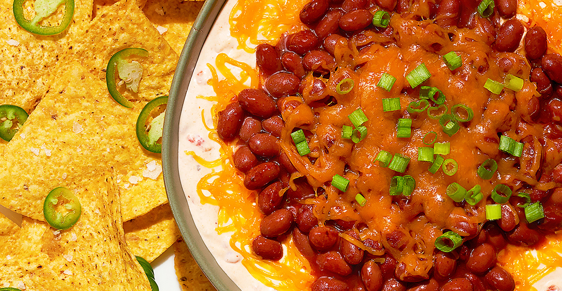 Bean and chili cream cheese dip with tortilla chips and jalapenos