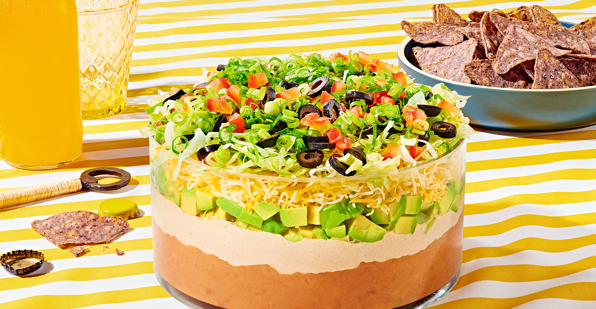 Refried bean dip with a layer of seasoned sour cream, topped with cheese, lettuce and black olives